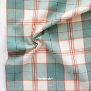 a close-up view of a fabric with a plaid pattern in shades of blue, green, and orange. The fabric appears to be made of cotton and has a crinkled texture.