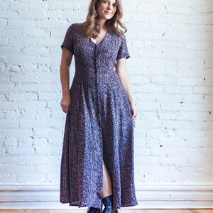May include: A woman wearing a long, floral print dress with a button-up front and short sleeves. She is wearing black combat boots.
