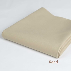 May include: A folded piece of beige fabric with a smooth texture. The fabric is labeled "Sand".