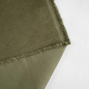 May include: Close-up of a piece of green corduroy fabric with a frayed edge.