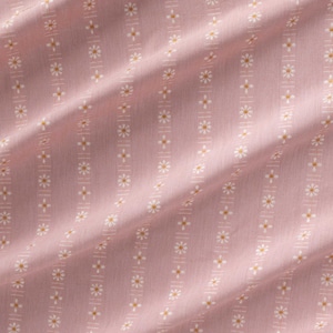 May include: Close-up of a pink fabric with a repeating pattern of white and gold daisy-like flowers arranged in vertical stripes. The fabric has a soft, slightly wrinkled texture, suggesting it is likely cotton or a similar material.