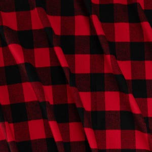 May include: Close-up of a red and black buffalo plaid fabric. The pattern consists of large, evenly spaced squares in a classic check design. The fabric has a soft, textured appearance.