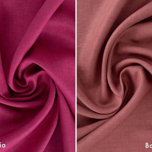 May include: Two swatches of fabric, one a deep magenta called "Sangria", the other a muted reddish-brown labeled "Bonfire". Both fabrics are tightly swirled, showcasing their texture and color variations. The fabric appears to be linen or a similar natural fiber.