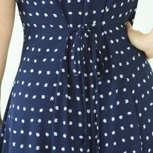 May include: A navy blue dress with a white polka dot pattern. The dress has a tie at the back.