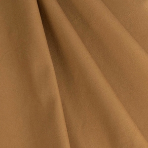 May include: A close-up of a brown fabric with a smooth texture. The fabric is folded in a way that creates a soft, flowing drape.