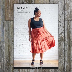 May include: A woman wearing a black tank top and a coral tiered skirt with a drawstring waist. The skirt is part of the "Mave Skirt" sewing pattern by True Bias, available in sizes 14-30.