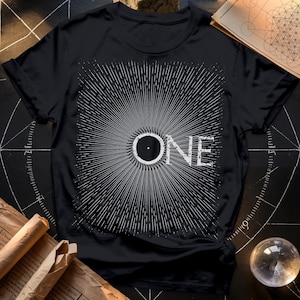 Könnte beinhalten: Schwarzes T-Shirt mit einem weißen Grafikdesign eines Kreises mit einem Punkt in der Mitte und dem Wort "ONE" in einer stilisierten Schrift.
