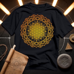 May include: A black t-shirt with a gold mandala design featuring a flower of life pattern. The mandala is intricate and detailed, with a geometric design that is both beautiful and symbolic.