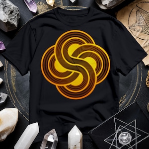 May include: A black t-shirt with a yellow and brown geometric design. The design is a series of overlapping circles that create a swirling effect.