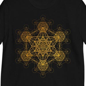 May include: A black t-shirt featuring a gold geometric design of a flower of life pattern.
