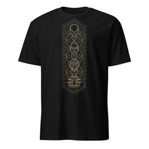 Peut inclure: T-shirt noir avec un motif doré représentant trois visages stylisés superposés : un extraterrestre, un humain et un singe. Le motif inclut des champignons et un fond géométrique.