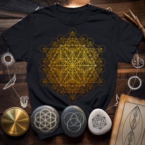 May include: Black t-shirt with a gold geometric design. The design is a complex pattern of overlapping circles, triangles, and squares.