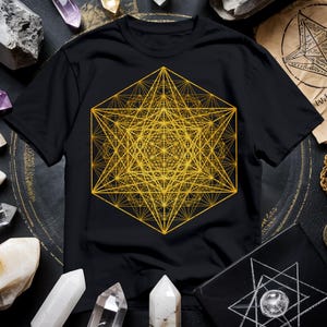 Może przedstawiać: Czarny T-shirt z złotym wzorem geometrycznym. Wzór to złożony wzór z nakładających się linii i kształtów, tworząc wizualnie skomplikowany i symetryczny wzór.