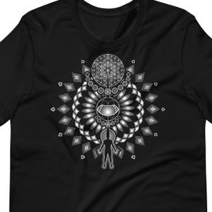 May include: Black t-shirt with a white geometric design featuring a stylized human figure, a circle with an eye, and a flower of life pattern.