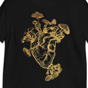 Może przedstawiać: Czarny t-shirt z złotym wzorem anatomicznego serca otoczonego grzybami.