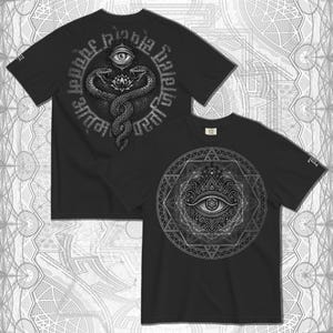 以下が含まれることがあります： 詳細なデザインが施された黒いTシャツ2枚。1枚は、テキストに囲まれた、上部に目のある蓮の花の周りに絡み合ったヘビが特徴です。もう1枚のシャツは、幾何学模様の中に目が表示されています。