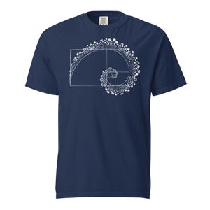 Könnte beinhalten: Marineblaues T-Shirt mit weißer Grafik eines Spiraldesigns mit floralen Akzenten, das den Goldenen Schnitt darstellt. Das T-Shirt besteht aus einem weichen, bequemen Material. Das Design ist eine mathematische Darstellung.