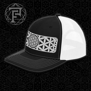 May include: Black and white trucker hat with a white embroidered flower of life design on the front. The hat has a black front and a white mesh back.