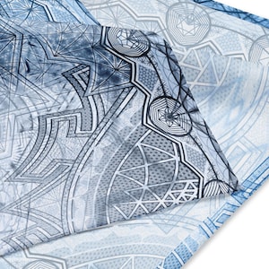 May include: A blue and white patterned fabric with a geometric design. The fabric is folded over itself, creating a layered effect.