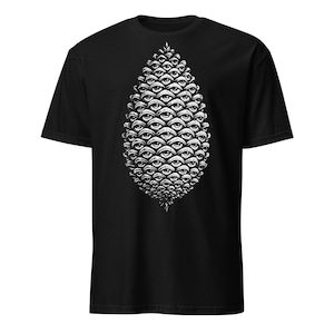 Puede incluir: Camiseta negra con un diseño gráfico blanco de forma de piña compuesto por numerosos ojos. El diseño está centrado en la parte delantera de la camiseta. La camiseta tiene mangas cortas y cuello redondo.