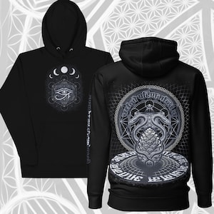 Puede incluir: Sudadera con capucha negra con un diseño geométrico de ojo y lunas crecientes en la parte delantera. La parte trasera muestra una ilustración detallada de dos serpientes y una piña dentro de un patrón circular. La sudadera tiene un cordón.