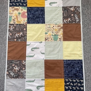 May include: A patchwork quilt featuring a range of animal and geometric patterns. The quilt is composed of 16 squares, each with a unique design. The colours in the quilt include yellow, brown, green, white, and black.