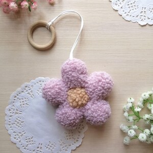 Pode incluir: Uma flor de cor roxa clara e felpuda com um centro de cor laranja claro, presa a um anel de madeira com um cord&atilde;o branco.