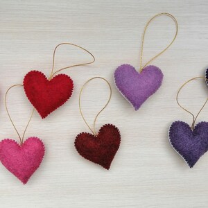 May include: Seven felt heart ornaments in various colors, including pink, red, purple, and blue, with gold string for hanging.