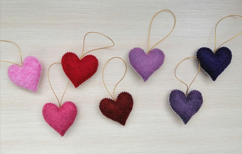 May include: Seven felt heart ornaments in various colors, including pink, red, purple, and blue, with gold string for hanging.