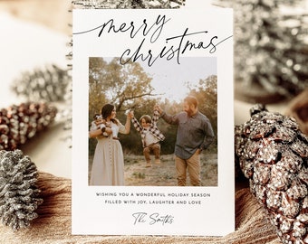 May include: A white Christmas card with a photo of a family of three. The card reads "merry christmas" in black script and "Wishing you a wonderful holiday season filled with joy, laughter and love. The Smiths".