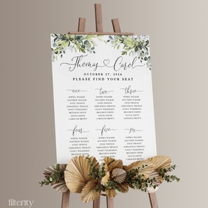 May include: A wedding seating chart with a green and white floral design. The chart is titled "Thomas & Carol" and lists the names of guests under the headings "One", "Two", "Three", "Four", "Five", and "Six".