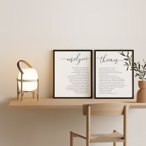 May include: Two framed prints with the names "carolyne" and "thomas" in elegant script, each containing a poem. A modern lamp with a cream-colored shade and wooden frame sits on a wooden shelf. A wooden chair is in the foreground.