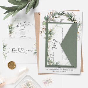 May include: A wedding invitation suite with a green and gold floral design. The invitation features a wreath of greenery and gold accents. The text on the invitation reads "The Wedding" and includes the date, location, and names of the couple. The RSVP card is included in the suite.