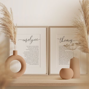 May include: Two framed prints with the names "carolyne" and "thomas" in elegant script. Each print features a poem in black text on a cream background. Decorative vases and dried pampas grass add to the aesthetic, creating a warm and inviting display.