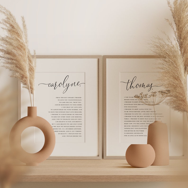 May include: Two framed prints with the names "carolyne" and "thomas" in elegant script. Each print features a poem in black text on a cream background. Decorative vases and dried pampas grass add to the aesthetic, creating a warm and inviting display.