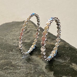 May include: Two silver rings with a beaded design. The rings are stacked on top of each other.