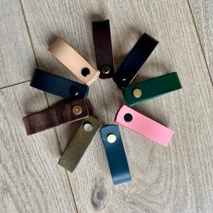 以下が含まれることがあります： 茶色、黒、緑、ピンク、ベージュなど、さまざまな色の革製の引き出しノブ10個の詰め合わせ。各ノブには金属製のボタンが付いています。