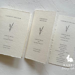 May include: Three cream-colored paper programs for a wedding ceremony. The programs feature a simple floral design and the text "Ceremony Program". The programs list the names of the couple, Ashley Mack and Nathan Watt, the date of the wedding, and the location. The bottom program lists the order of the ceremony, including the processional, giving away, special prayer, message, exchange of vows, rings, signing, special song, unity, pronouncing, closing remarks, and recessional.