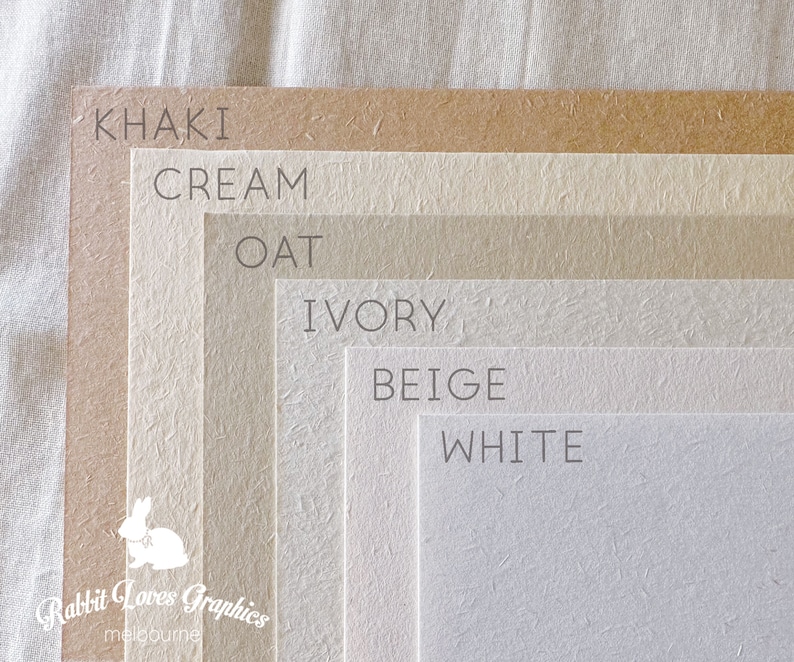 May include: A color chart showing six different shades of paper, from darkest to lightest: khaki, cream, oat, ivory, beige, and white. The paper has a textured surface.