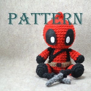 Könnte beinhalten: Eine gehäkelte Deadpool-Figur mit einem rot-schwarzen Anzug, weißen Augen und einem schwarzen Gürtel. Die Figur hält ein silbernes Schwert in der Hand. Das Wort "PATTERN" ist in grünen Buchstaben über der Figur geschrieben.