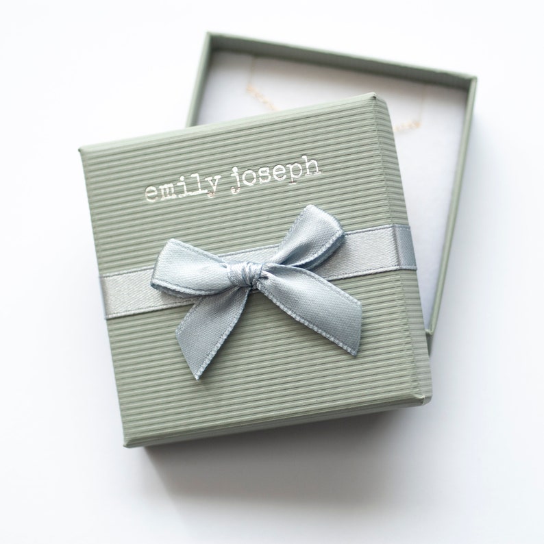 May include: A light green gift box with a light blue ribbon and bow. The box has the text "emily joseph" printed on the top.