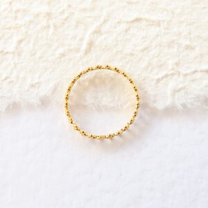 May include: A gold ring with a beaded design.