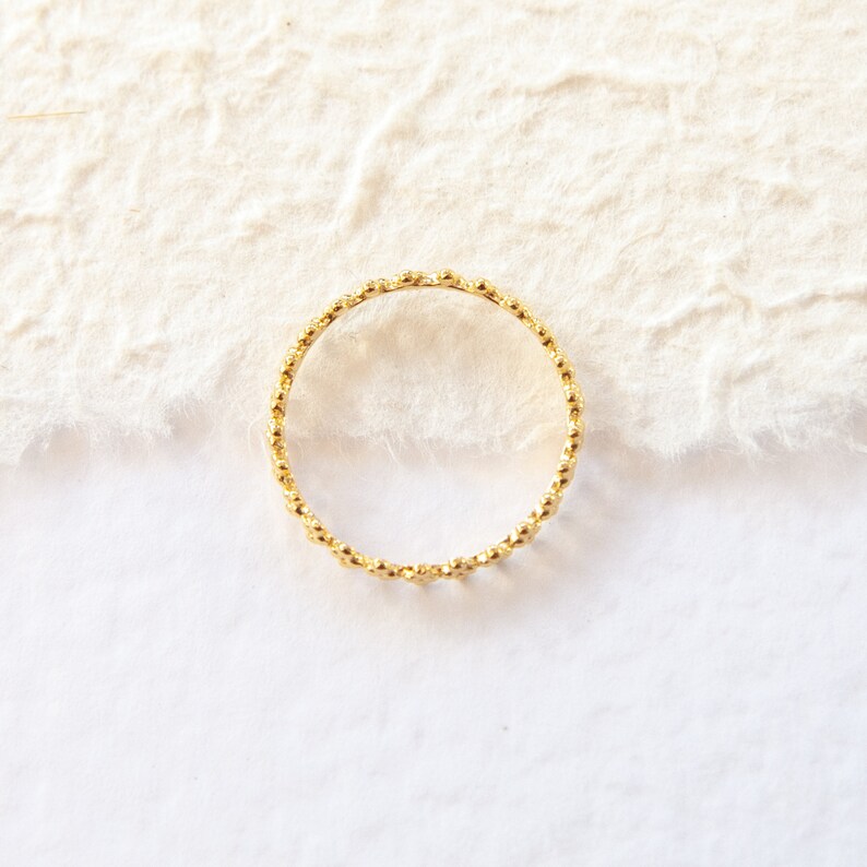 May include: A gold ring with a beaded design.