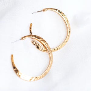 May include: A pair of gold-toned hoop earrings with a hammered texture.
