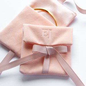 May include: A pink velvet jewellery pouch with a satin ribbon tied in a bow. The pouch is personalised with the initials "EJ".