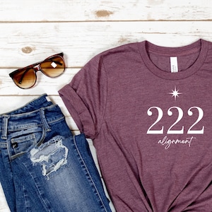 May include: A maroon t-shirt with the text "222 alignment" and a small star graphic printed on the front.