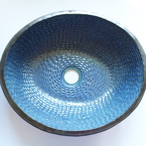 May include: A blue ceramic sink with a textured surface. The sink has a round drain hole in the center.