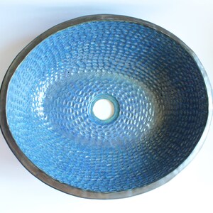 May include: A blue ceramic vessel sink with a textured surface and a circular drain hole in the center.