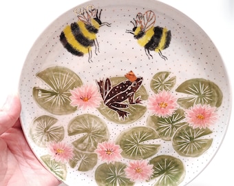 Frog in the lake. Fairy-tale illustrated ceramics, fauna and flora, bumblebees. Ceramic plate.