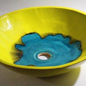 May include: A yellow ceramic sink with a turquoise blue center and a drain hole. The sink has a unique, organic shape.